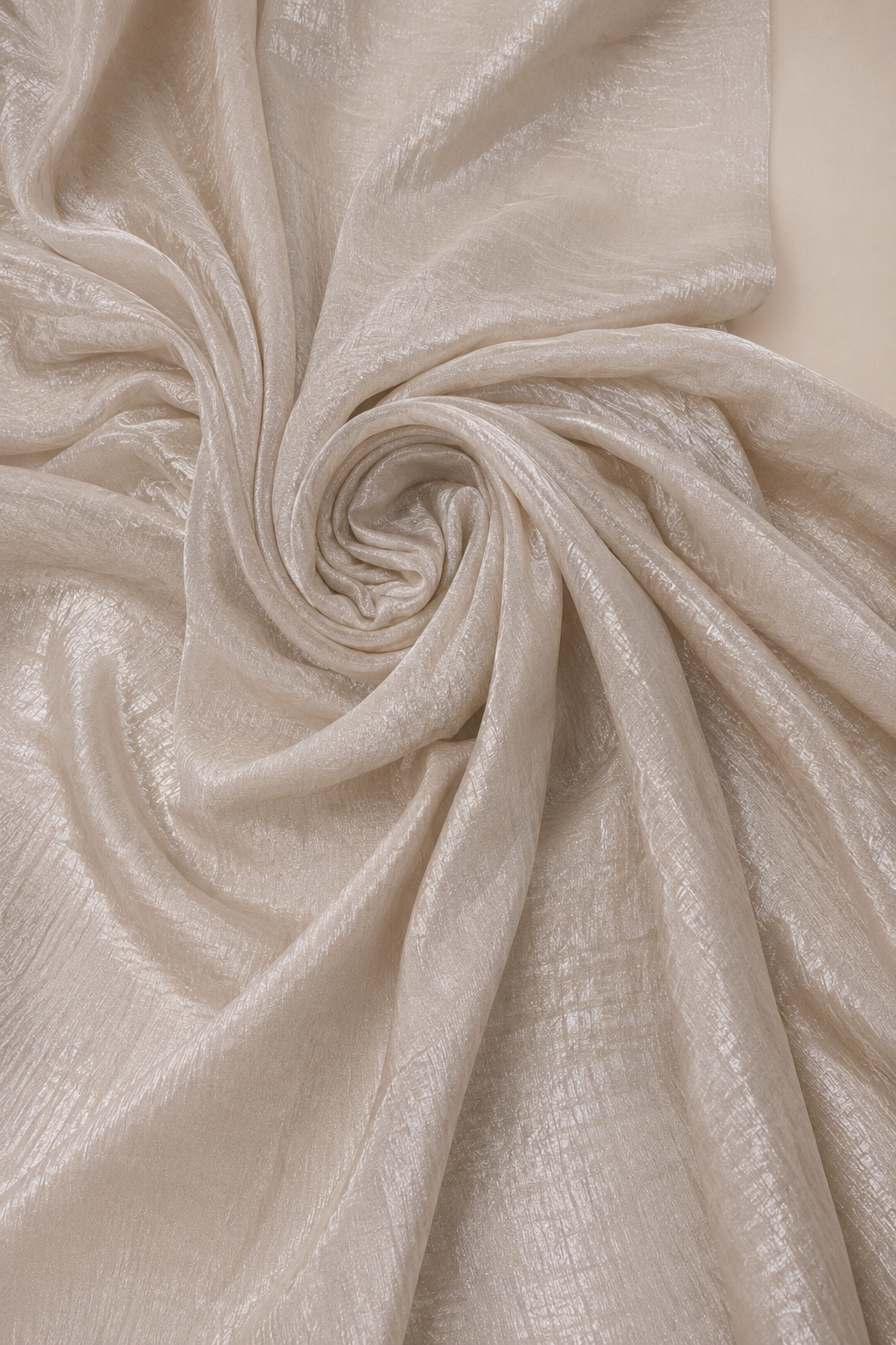 A crush tissue saree in shimmering champagne, its metallic sheen caught in a soft spiral of crinkled folds.