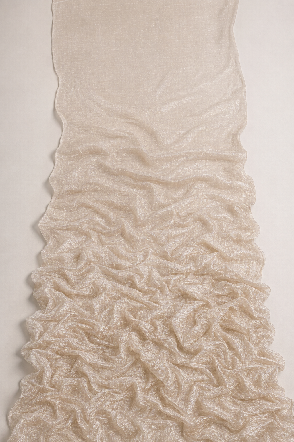 A length of champagne crush tissue lying smooth at the top and gathering into its all-over crinkle below — the fabric before and after it’s crushed and set.