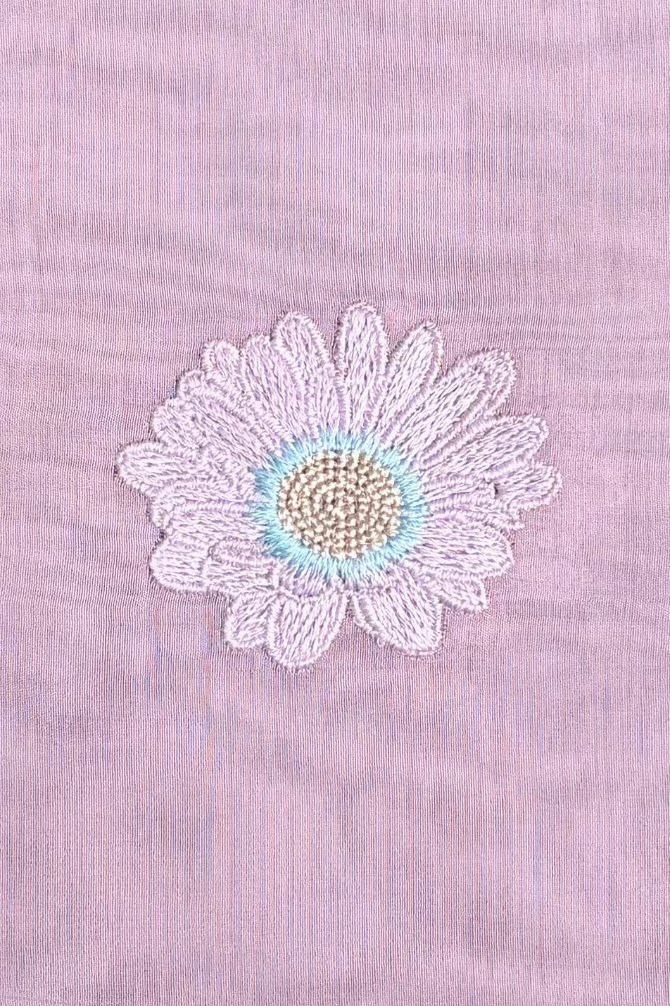 Macro of a single lavender daisy embroidered in viscose thread on mauve mul cotton.