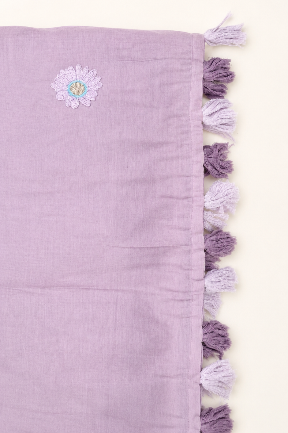 Close-up of a mauve mul cotton saree's tasselled pallu in lavender and purple.