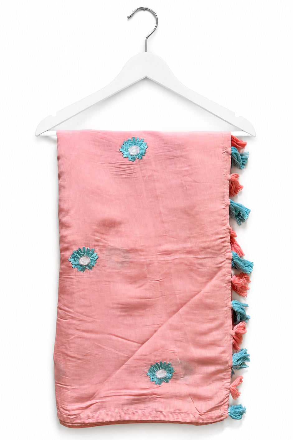 Blush pink mul cotton saree on a hanger, with aqua daisy embroidery and a pallu edge of blush-pink and aqua tassels.