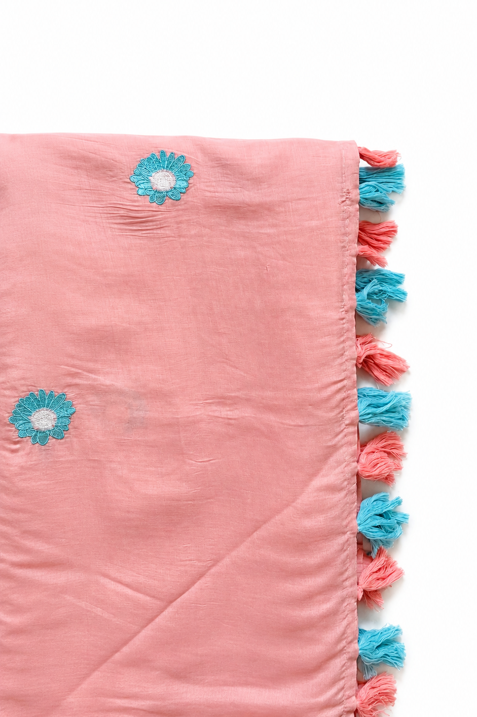 Folded blush mul cotton saree showing aqua daisy embroidery and a tasselled pallu edge in blush-pink and aqua.