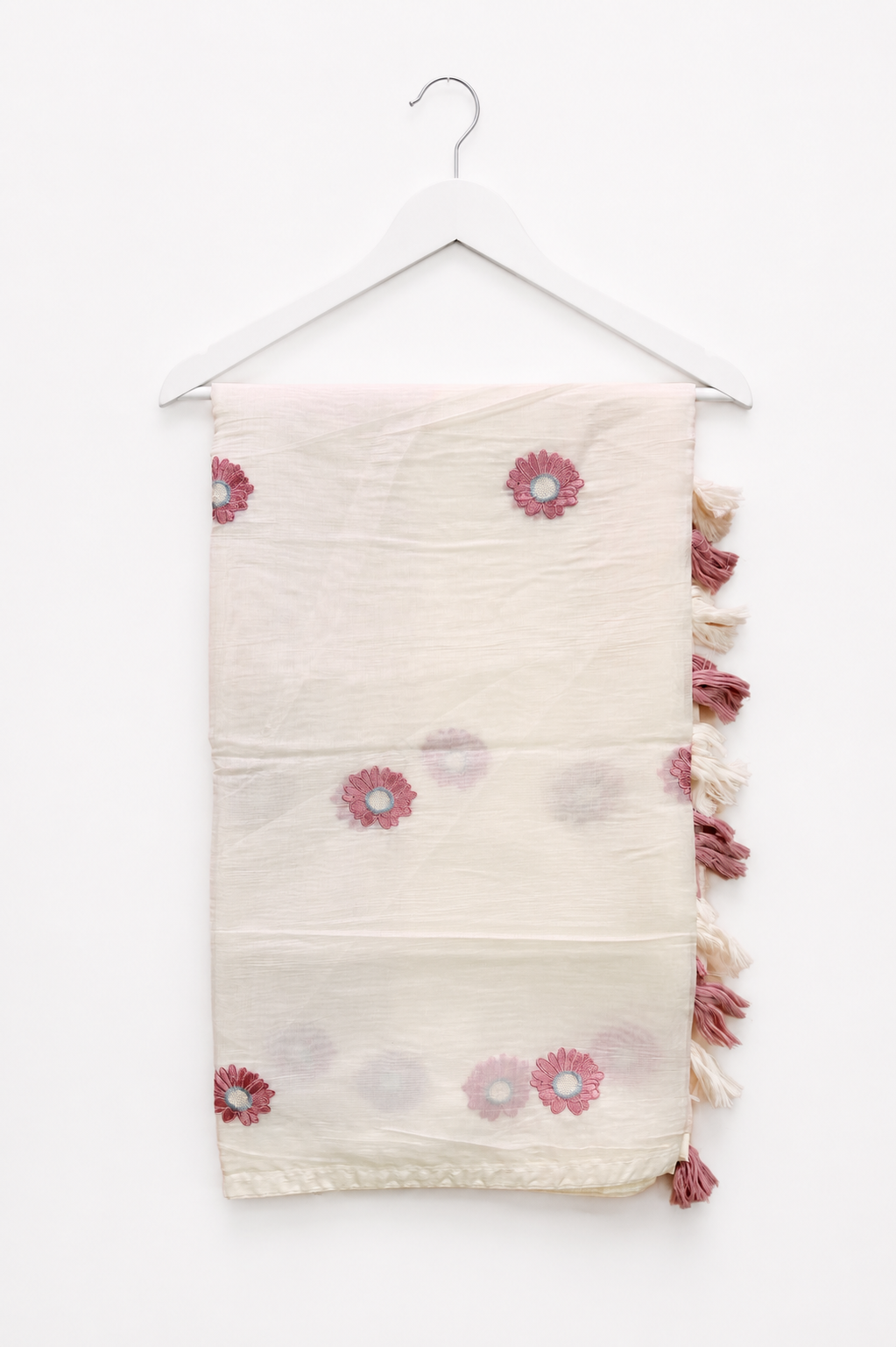 Ivory mul cotton saree with dusty-rose daisy embroidery and a cream-and-rose tasselled pallu, displayed on a hanger.