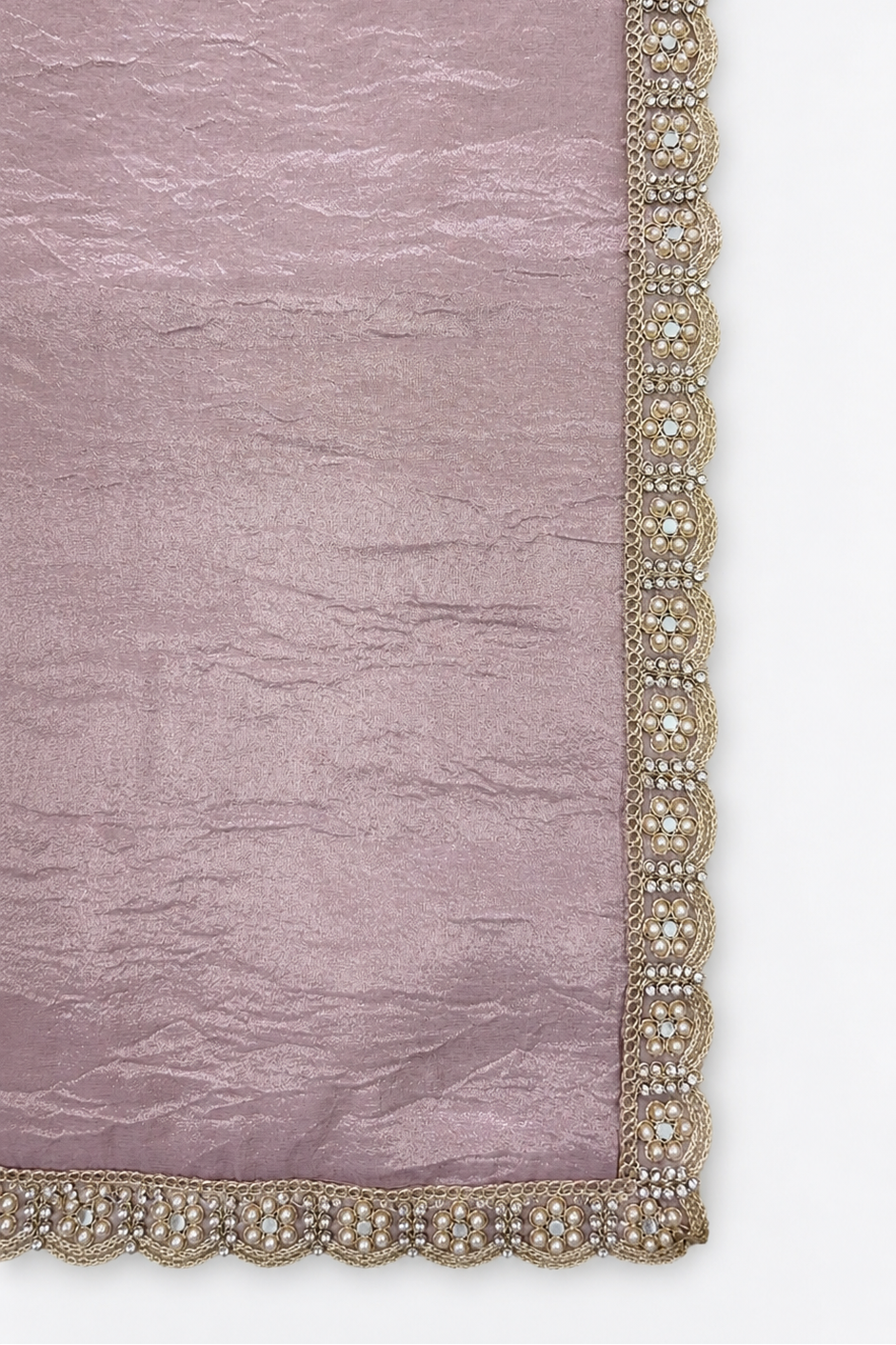 A close-up of a dusty pink fabric with a decorative scalloped border featuring gold and white beadwork.