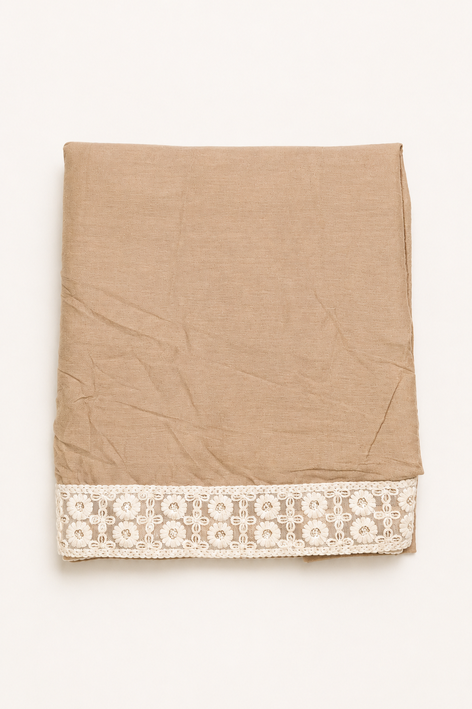 A folded beige fabric item, likely a blanket or throw, featuring a decorative cream lace border along the bottom edge, displayed against a clean off-white background.