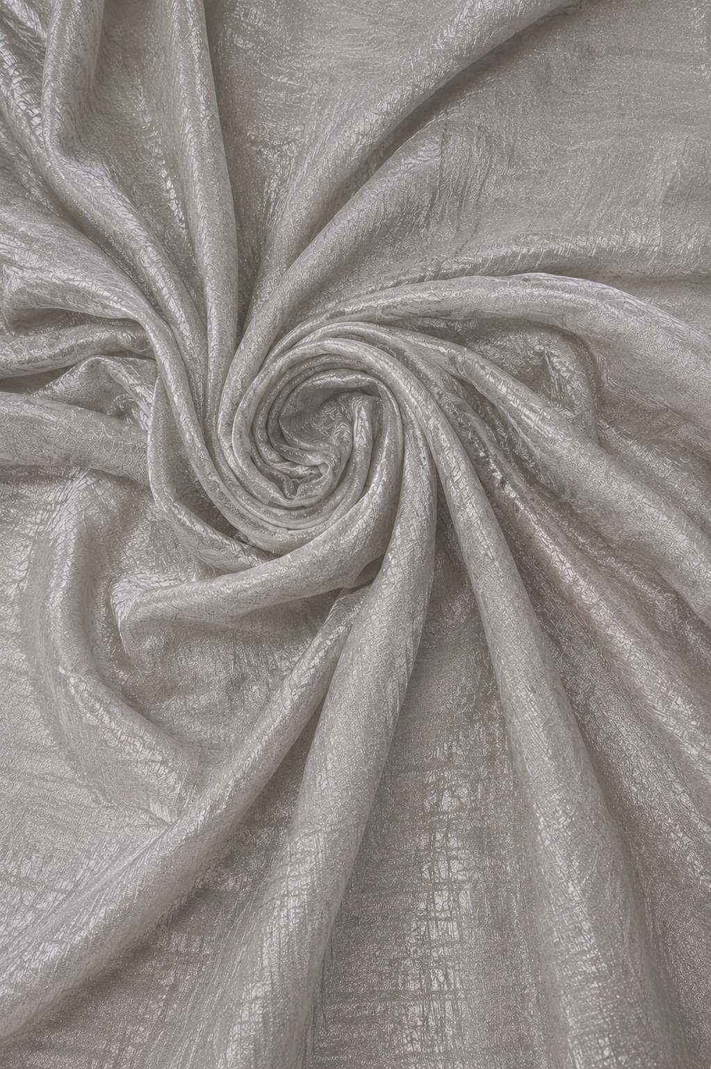 A close-up of shimmering light gray fabric arranged in a spiral drape, showing a subtle metallic sheen and textured weave.