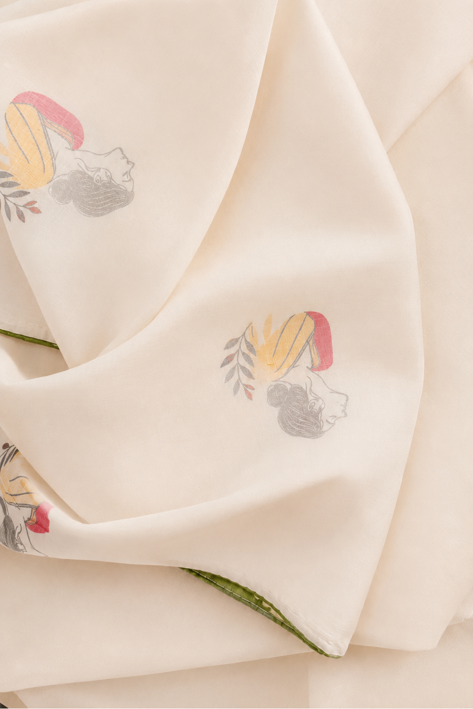 A close-up of a cream-colored fabric napkin or cloth with delicate embroidered floral motifs in pink, yellow, and gray, draped elegantly.